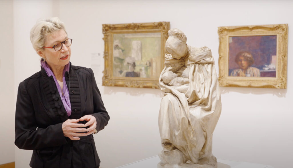 Class, Tour Woman with glasses in a dark suit discusses a terra cotta sculpture in our European Galleries.