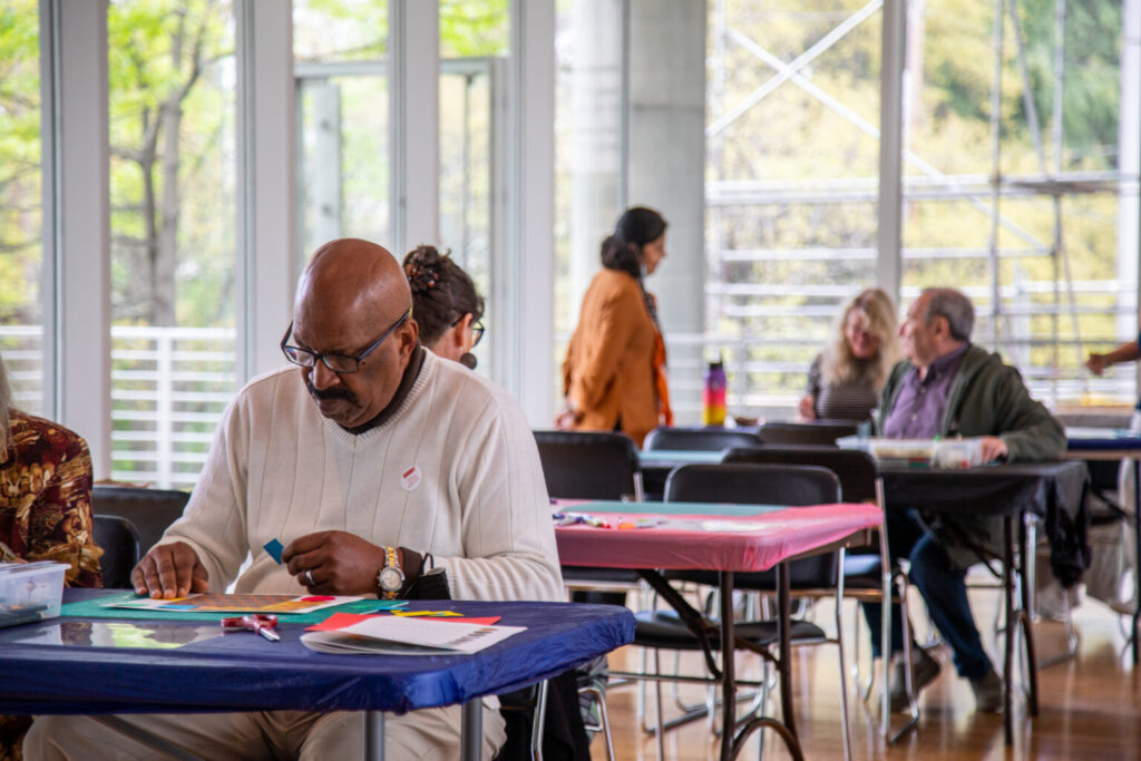 man making art with other people making art at different tables in the background