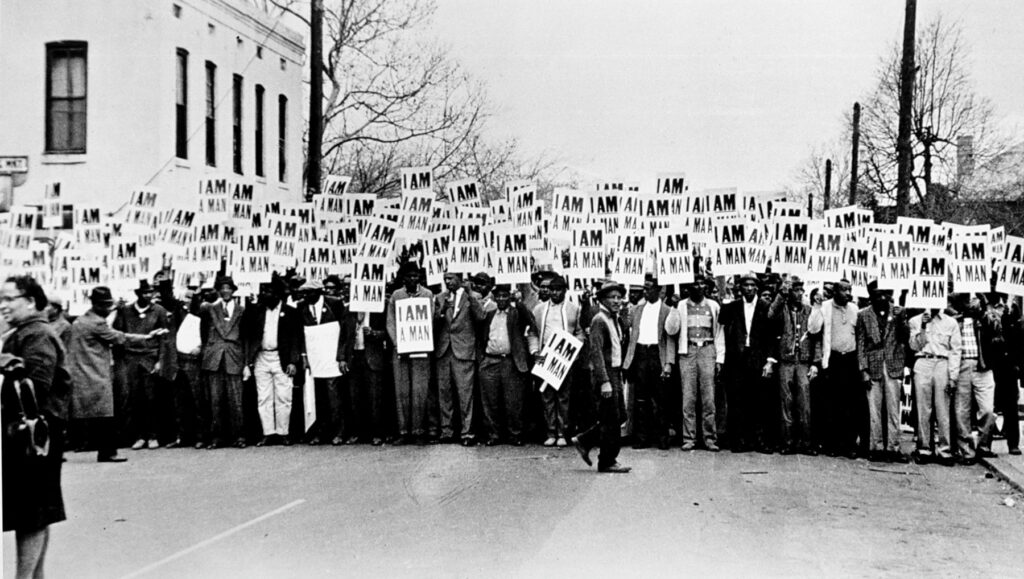 hundreds of black men march holding signs that read 