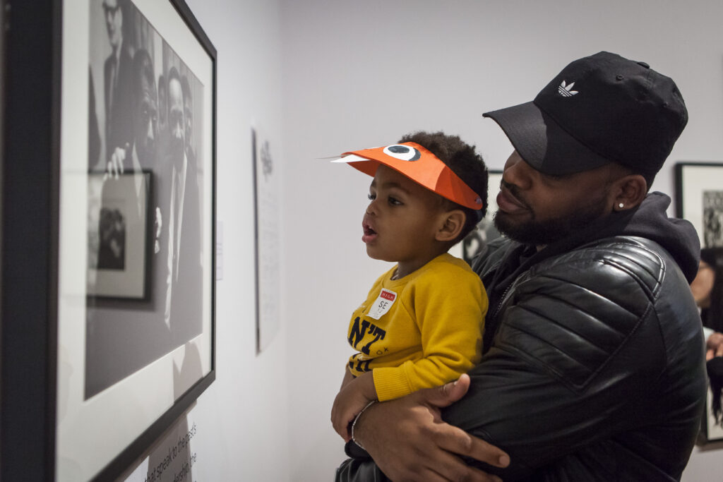 second sunday, family tour Man holds up his young son to look at a photograph hanging in the High Museum.