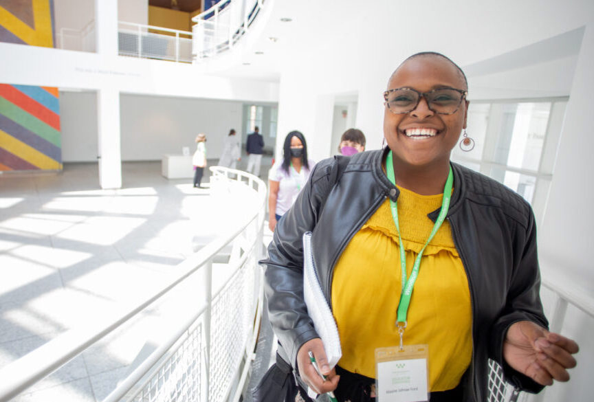 Woman with glasses smiles while walking up a ramp in the High Museum of Art's Atrium